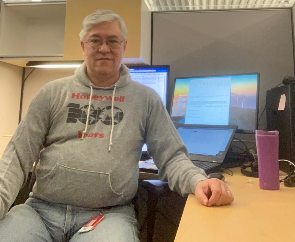 Steve seated at his office desk wearing a Honeywell centennial sweatshirt
